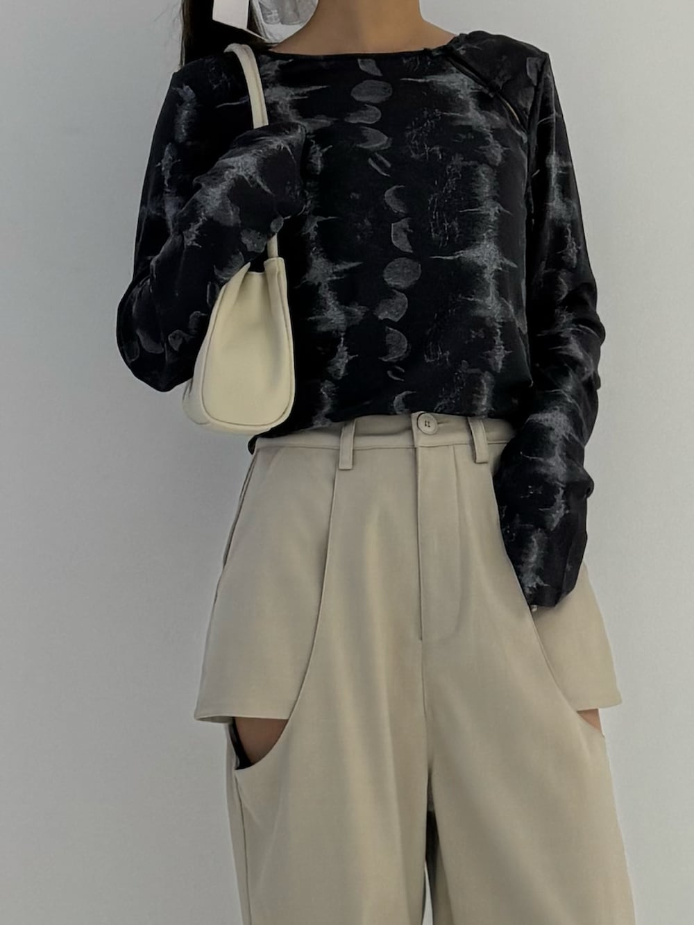 ベージュ系のスラックス、ブラック系のトップス、ベージュ系のトートバッグを着用したレディースの秋コーディネートの2枚目の写真