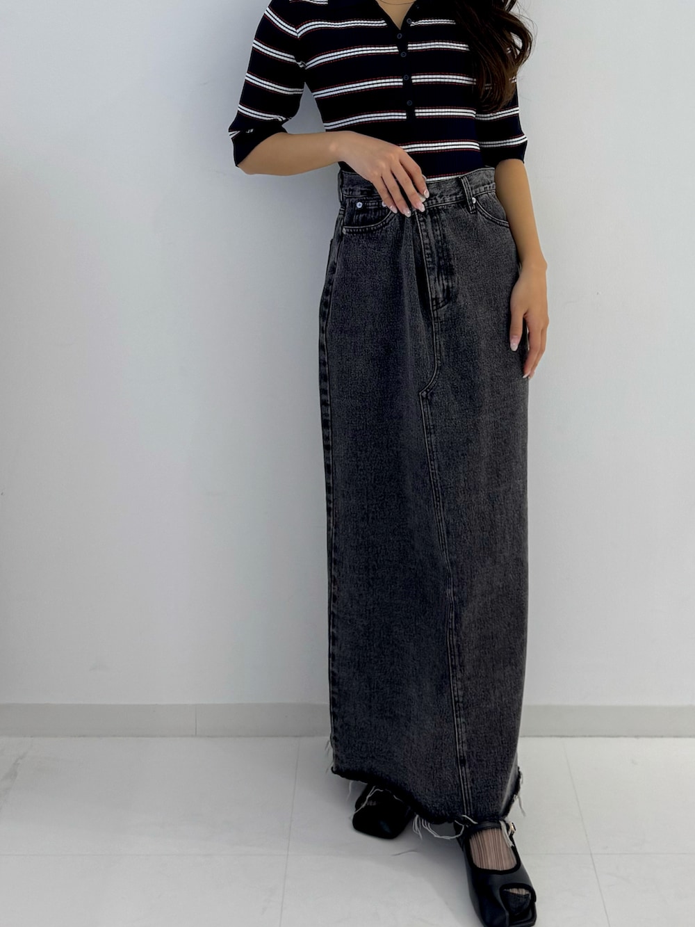 ブラック系のデニムスカート、ブラック系のパンプスを着用したレディースの春コーディネートの2枚目の写真