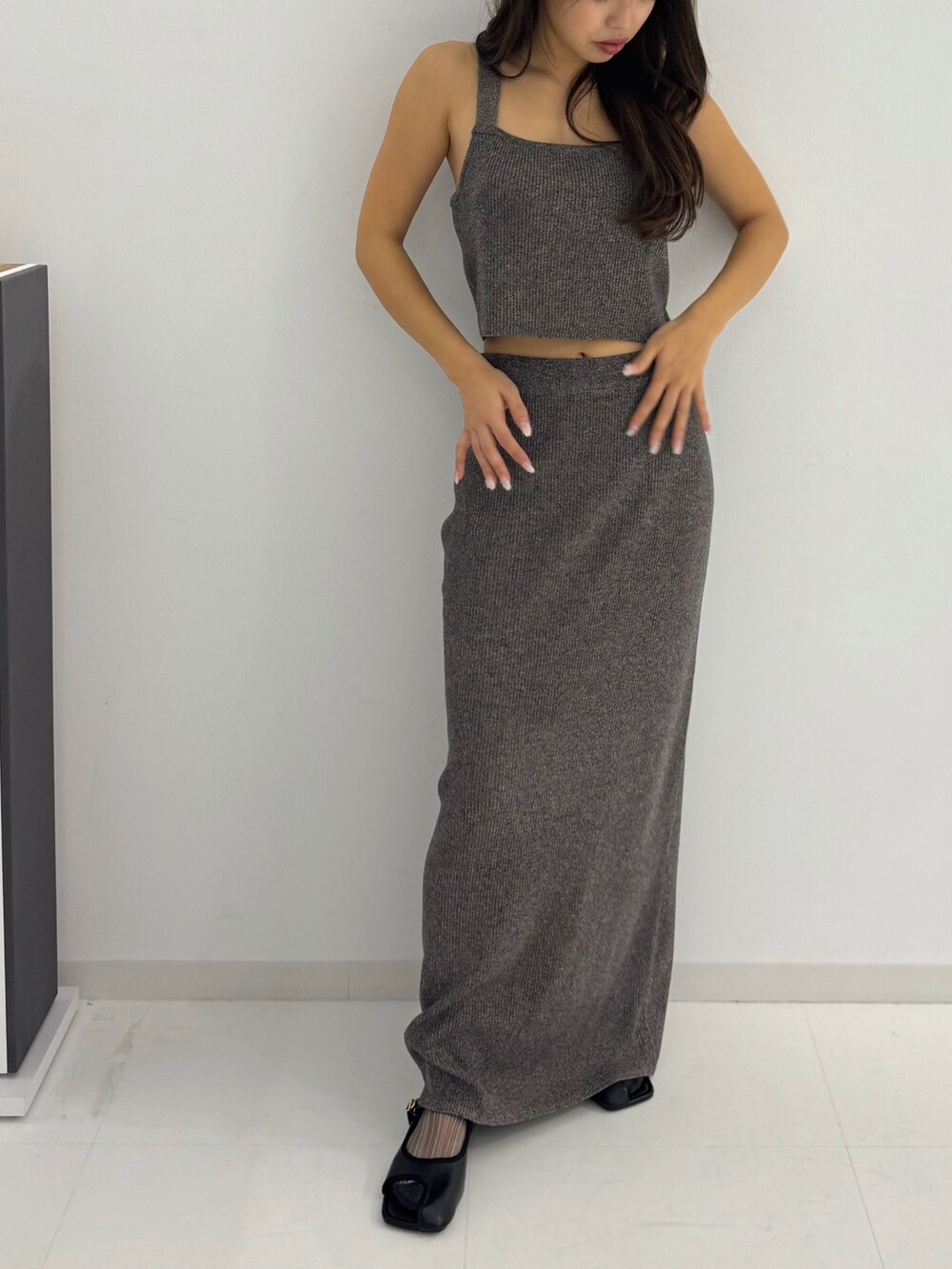 グレー系のトップス、グレー系のスカート、ブラック系のサンダルを着用したレディースの春コーディネートの2枚目の写真