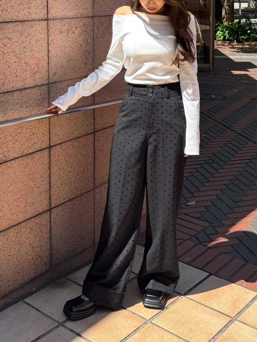 ホワイト系のトップス、ブラック系のスラックスを着用したレディースの春コーディネートの2枚目の写真