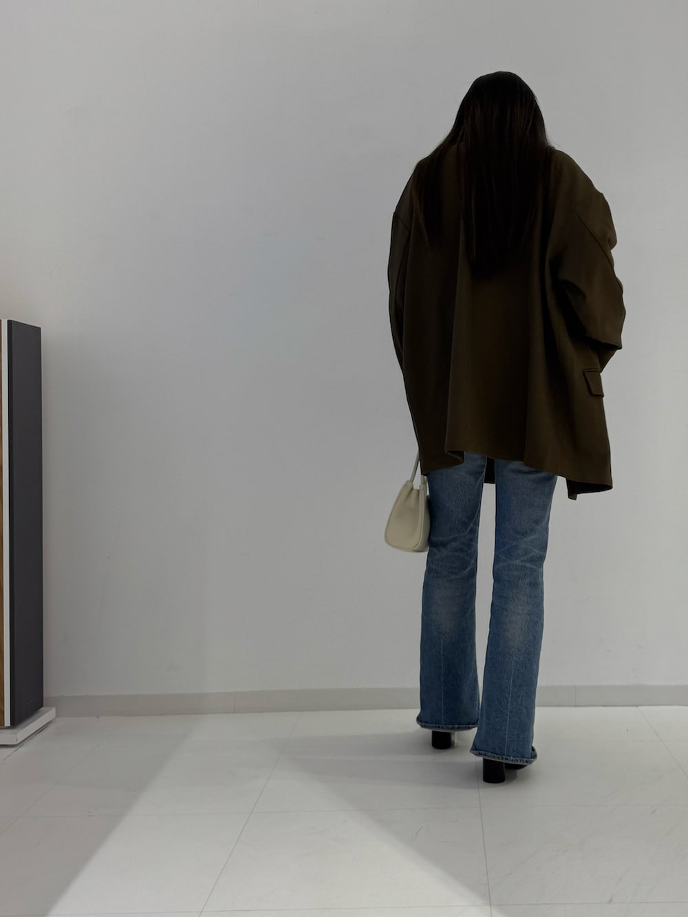 ブラック系のテーラードジャケット、ブラック系のブーツ、ベージュ系のトップスを着用したレディースの秋コーディネートの4枚目の写真