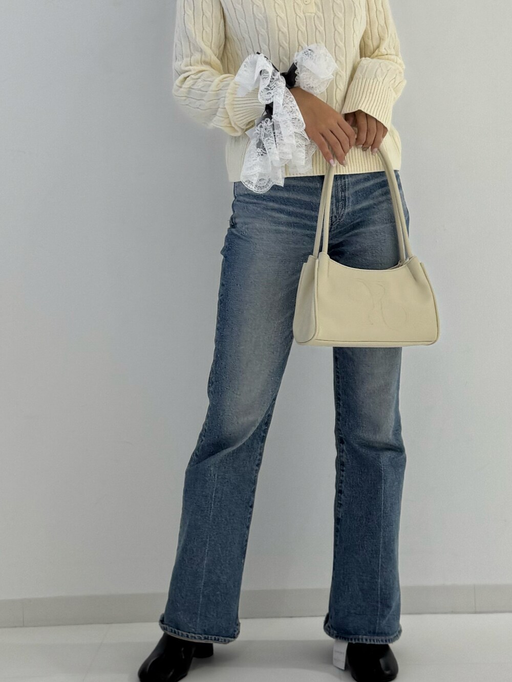 ブラック系のブーツ、ベージュ系のトップス、ベージュ系のトートバッグを着用したレディースの秋コーディネートの3枚目の写真