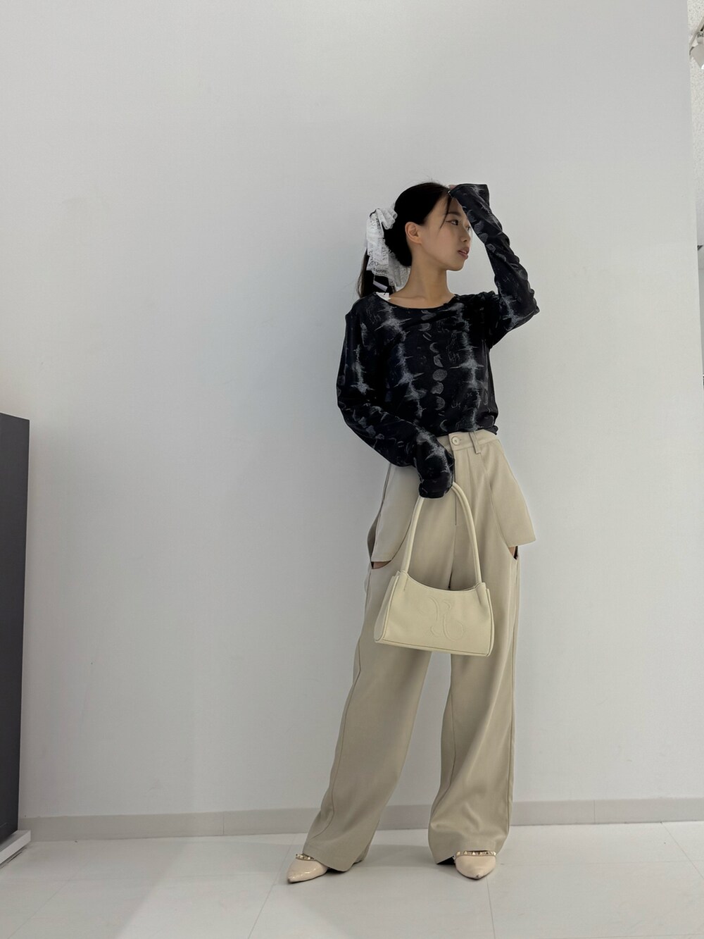 ベージュ系のスラックス、ブラック系のトップス、ベージュ系のトートバッグを着用したレディースの秋コーディネートの4枚目の写真