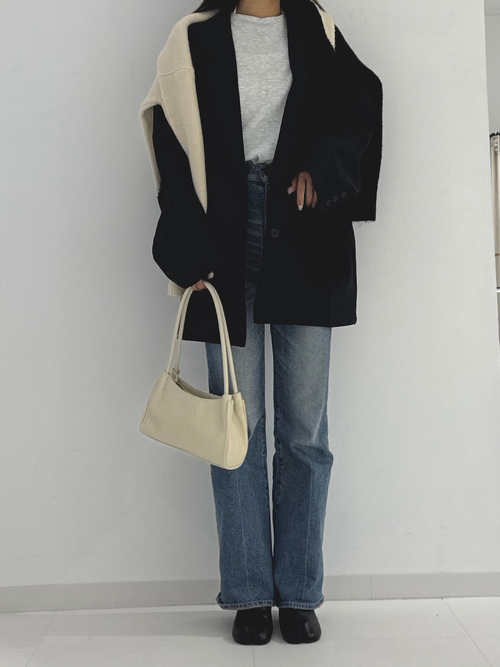ブラック系のブーツ、ベージュ系のトートバッグ、ブラック系のテーラードジャケットを着用したレディースの秋コーディネートの3枚目の写真