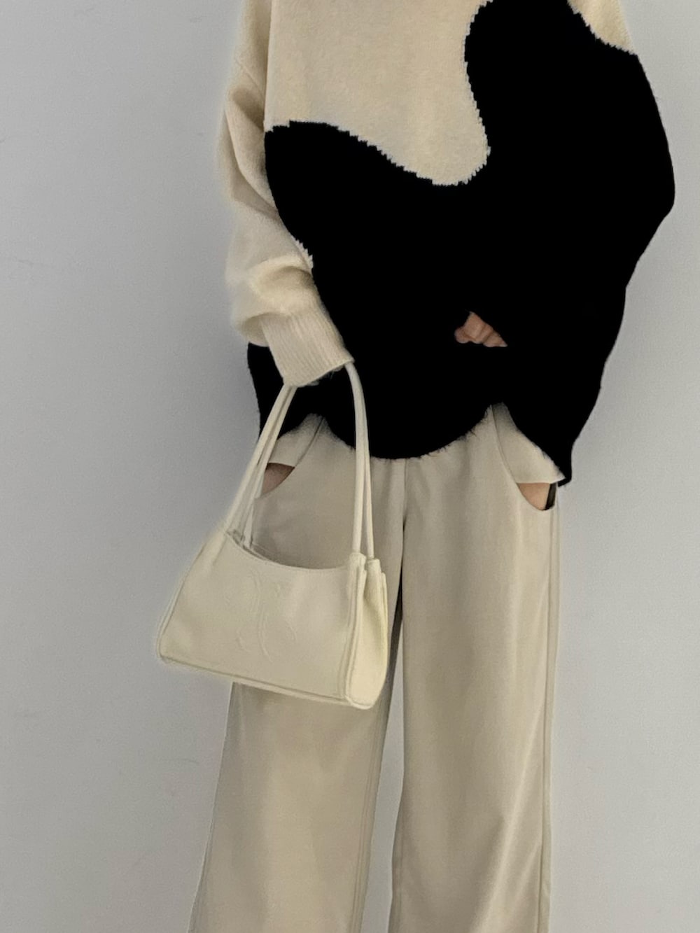 ベージュ系のスラックス、ブラック系のブーツ、ベージュ系のニット/セーターを着用したレディースの秋コーディネートの4枚目の写真