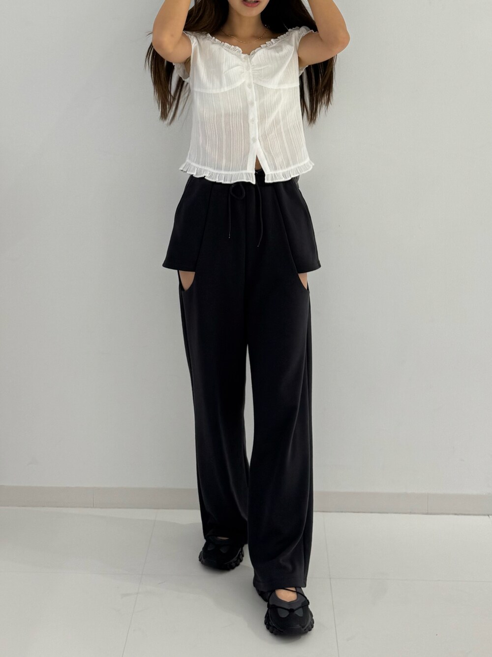 ホワイト系のトップス、ブラック系のパンツ、ブラック系のシューズを着用したレディースの夏コーディネートの2枚目の写真