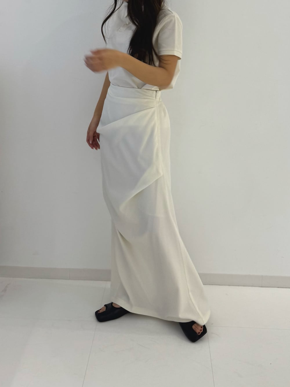 ホワイト系のスカート、ブラック系のサンダル、ホワイト系のポロシャツを着用したレディースの春コーディネートの2枚目の写真