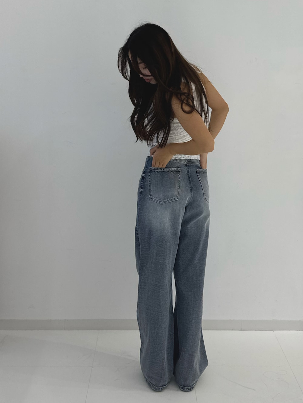 グレー系のデニムパンツ、ブラック系のローファー、ホワイト系のトップスを着用したレディースの春コーディネートの3枚目の写真