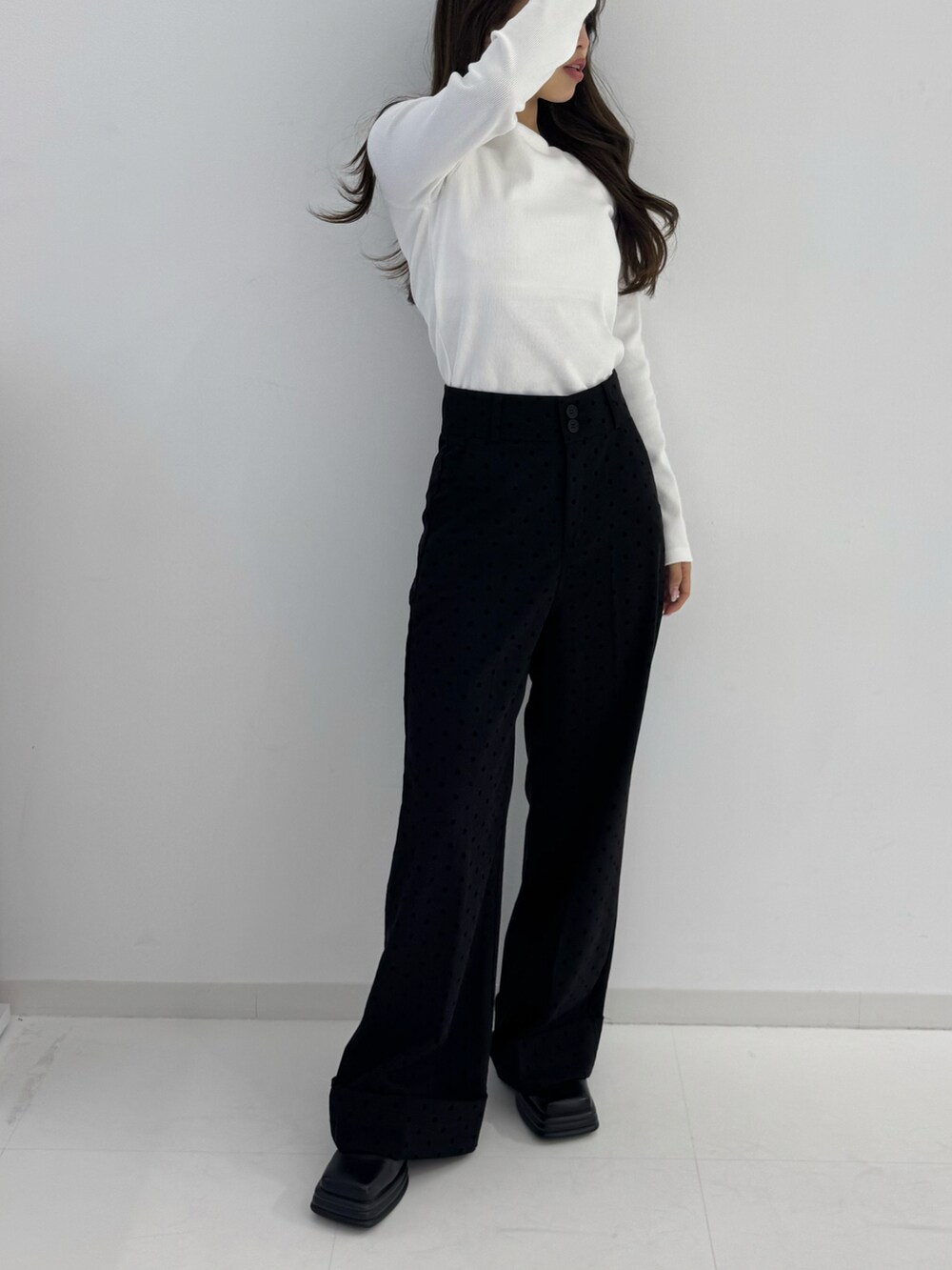 ホワイト系のトップス、ブラック系のスラックスを着用したレディースの春コーディネートの3枚目の写真