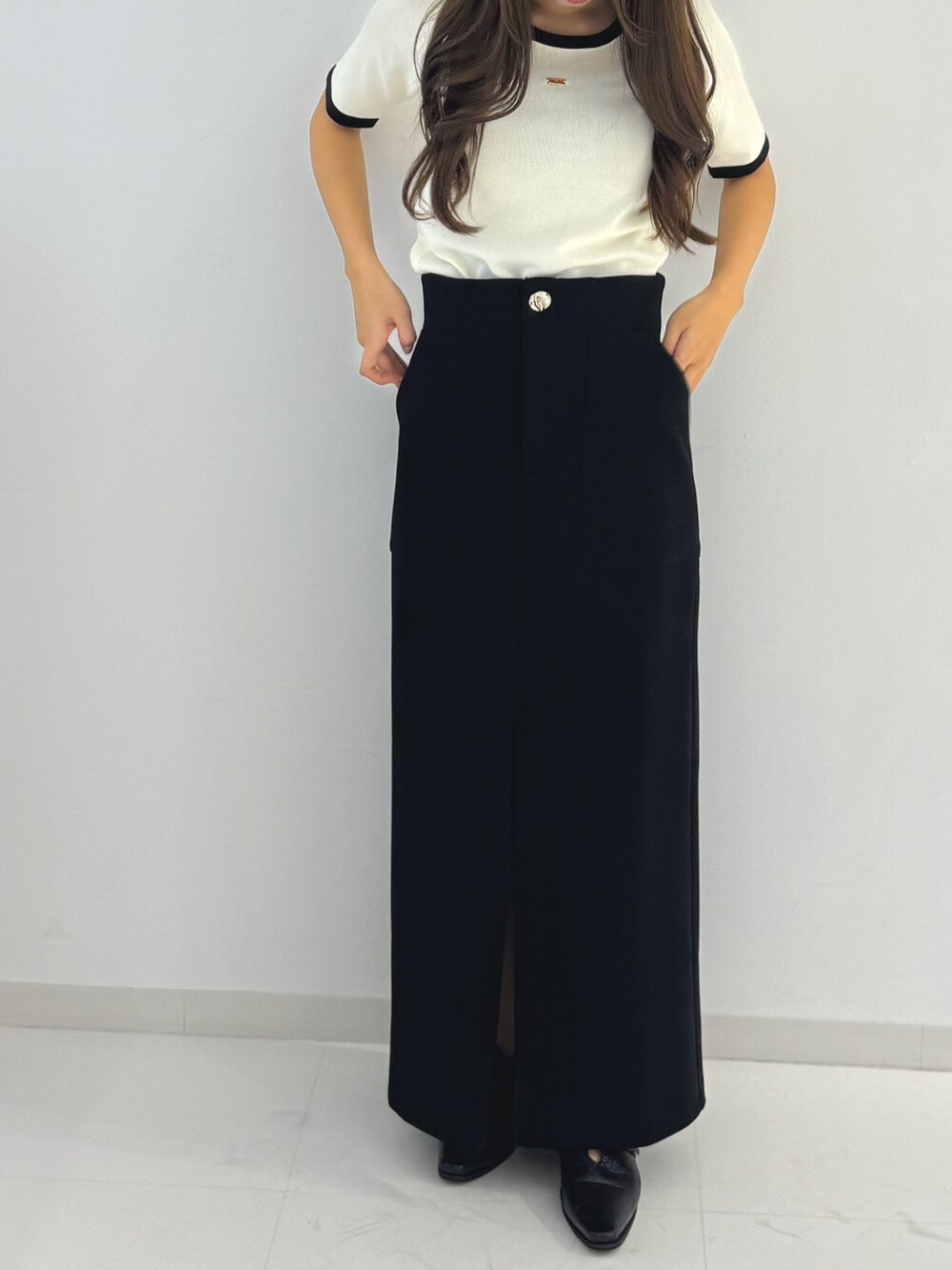 ブラック系のスカート、ホワイト系のトップス、ブラック系のローファーを着用したレディースの春コーディネートの2枚目の写真