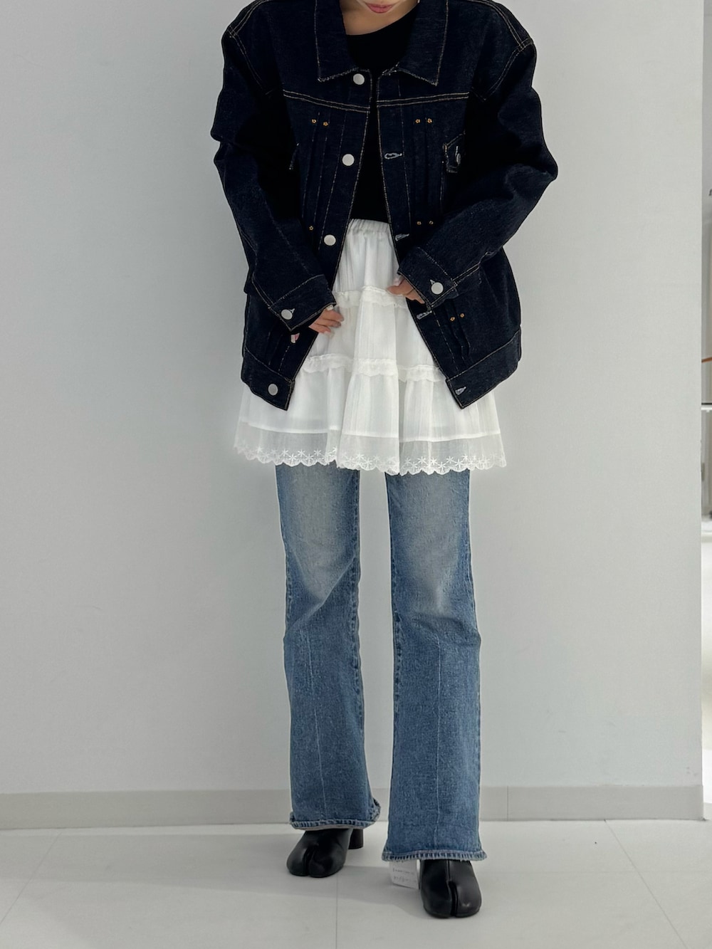 ブラック系のTシャツ/カットソー、ホワイト系のスカート、ブラック系のブーツを着用したレディースの秋コーディネートの2枚目の写真