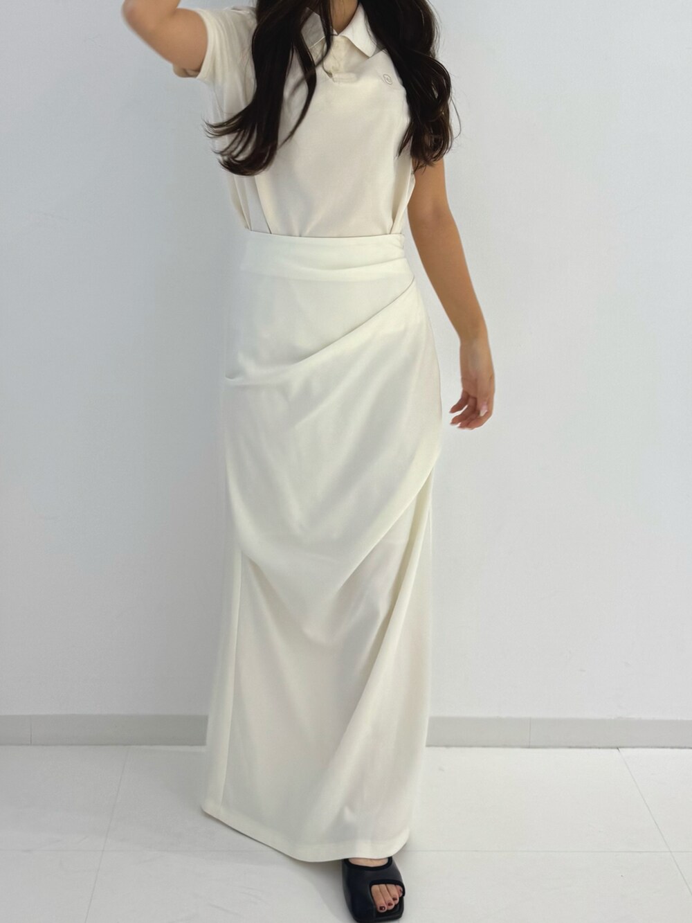 ホワイト系のスカート、ブラック系のサンダル、ホワイト系のポロシャツを着用したレディースの春コーディネートの3枚目の写真