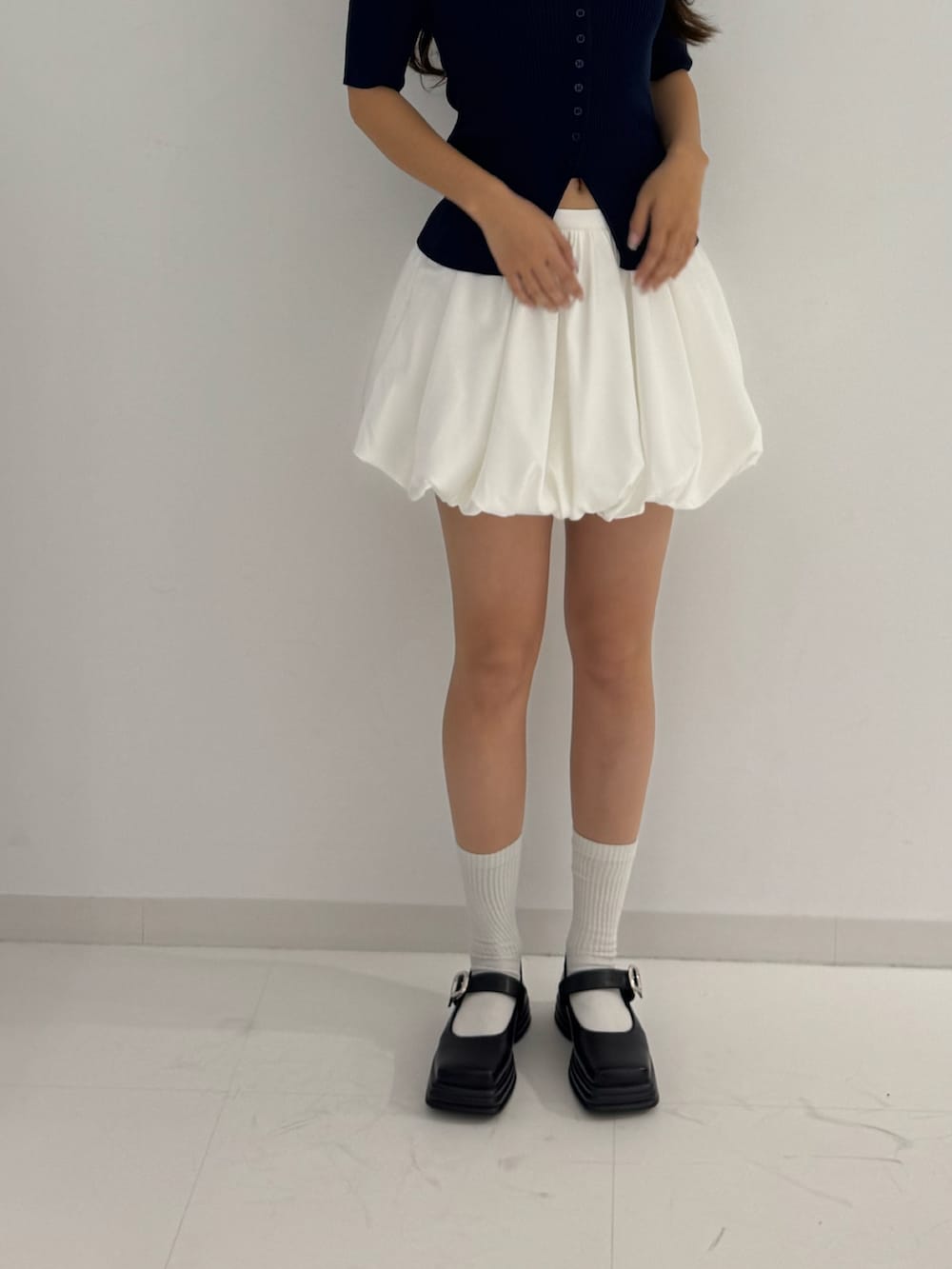 ブルー系のニット/セーター、ホワイト系のスカート、ブラック系のローファーを着用したレディースの春コーディネートの4枚目の写真