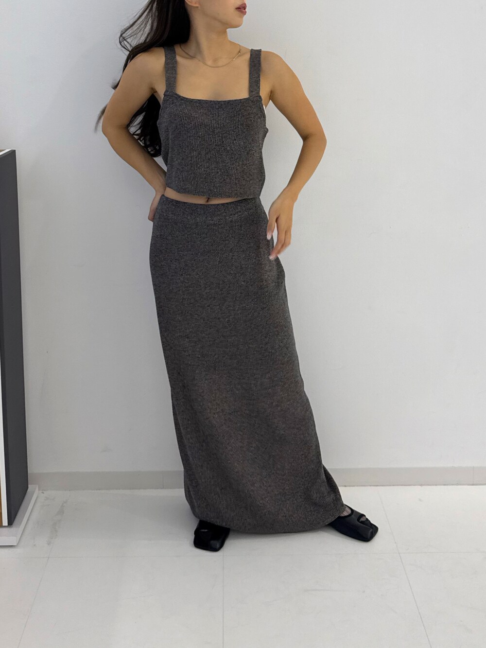 グレー系のトップス、グレー系のスカート、ブラック系のサンダルを着用したレディースの春コーディネートの3枚目の写真