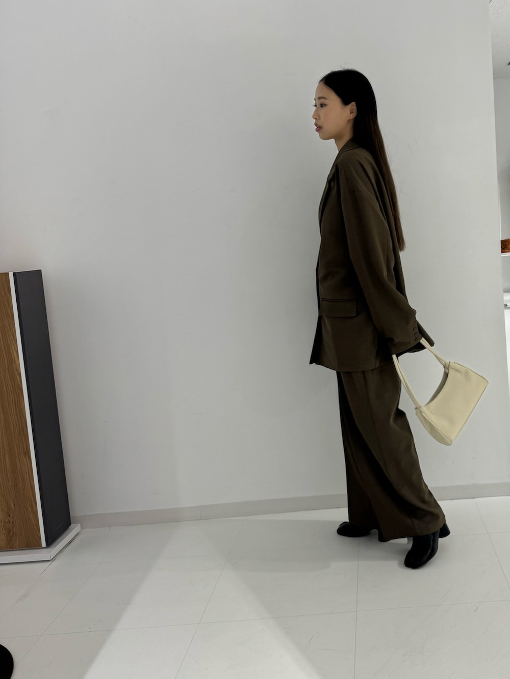 ブラック系のTシャツ/カットソー、ブラック系のテーラードジャケット、ブラウン系のスラックスを着用したレディースの秋コーディネートの2枚目の写真