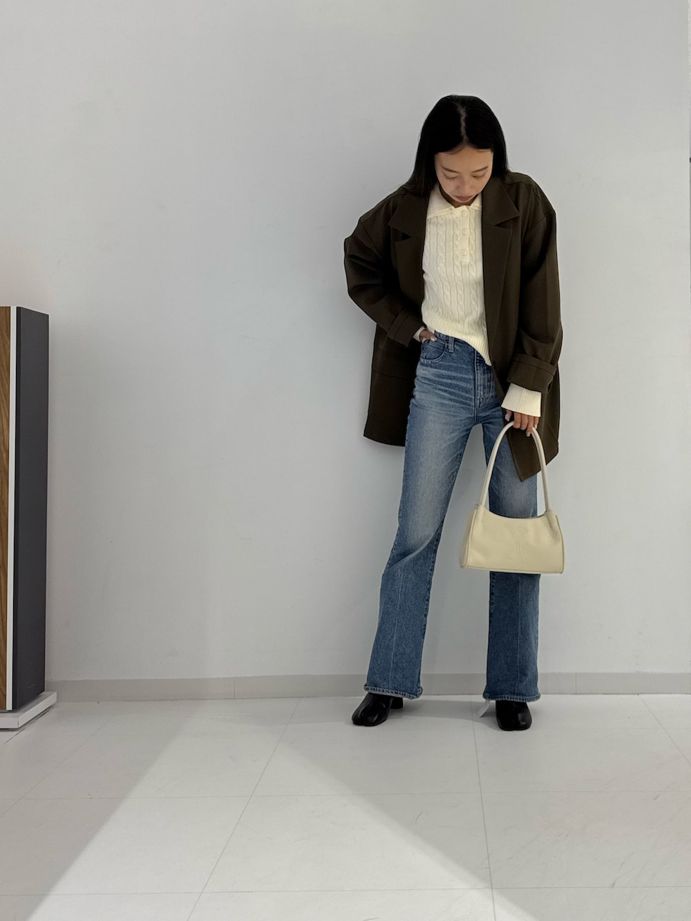 ブラック系のテーラードジャケット、ブラック系のブーツ、ベージュ系のトップスを着用したレディースの秋コーディネートの3枚目の写真