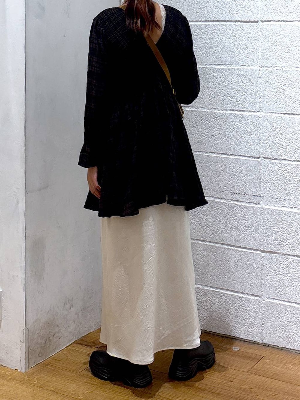 ブラック系のブーツ、ホワイト系のスカート、ブラウン系のショルダーバッグを着用したレディースの秋コーディネートの3枚目の写真