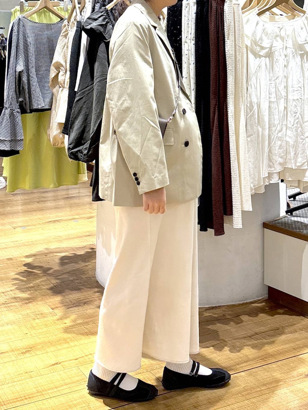 ホワイト系のスカート、ブラック系のスニーカー、ブラウン系のタンクトップを着用したレディースの春コーディネートの2枚目の写真