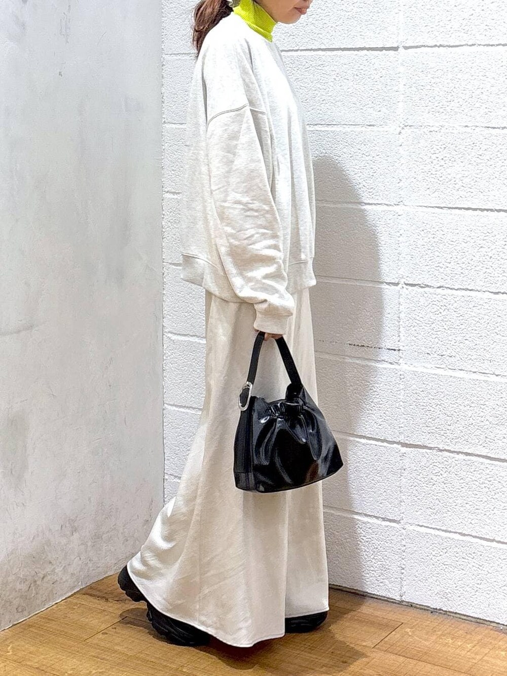 ブラック系のブーツ、ホワイト系のスカート、イエロー系のニット/セーターを着用したレディースの冬コーディネートの2枚目の写真