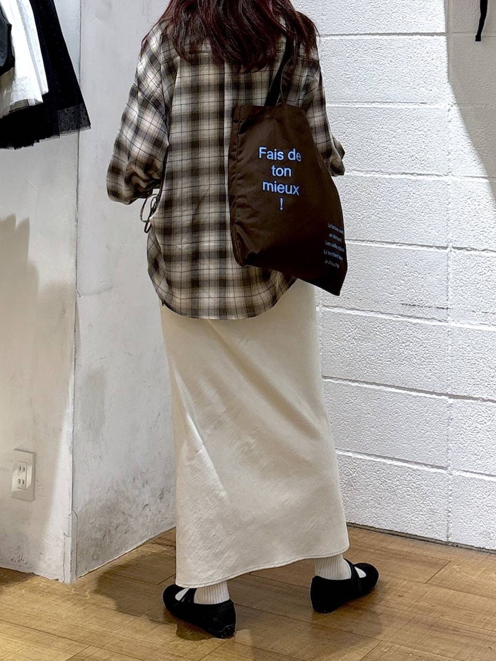 ホワイト系のスカート、ブラウン系のトートバッグ、ブラック系のスニーカーを着用したレディースの春コーディネートの3枚目の写真