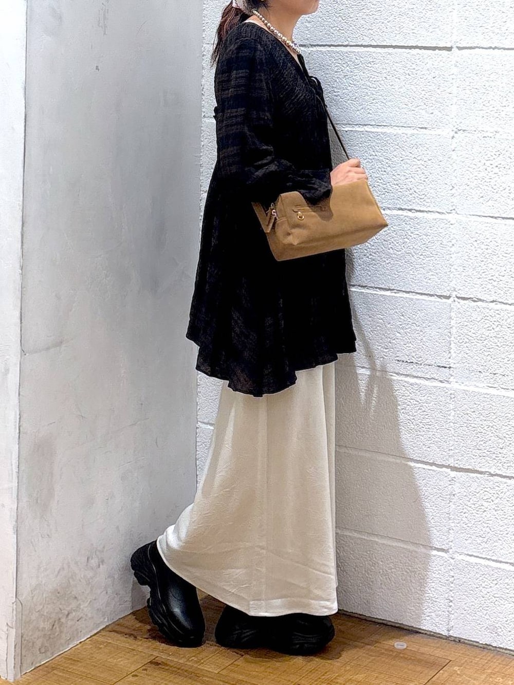 ブラック系のブーツ、ホワイト系のスカート、ブラウン系のショルダーバッグを着用したレディースの秋コーディネートの2枚目の写真