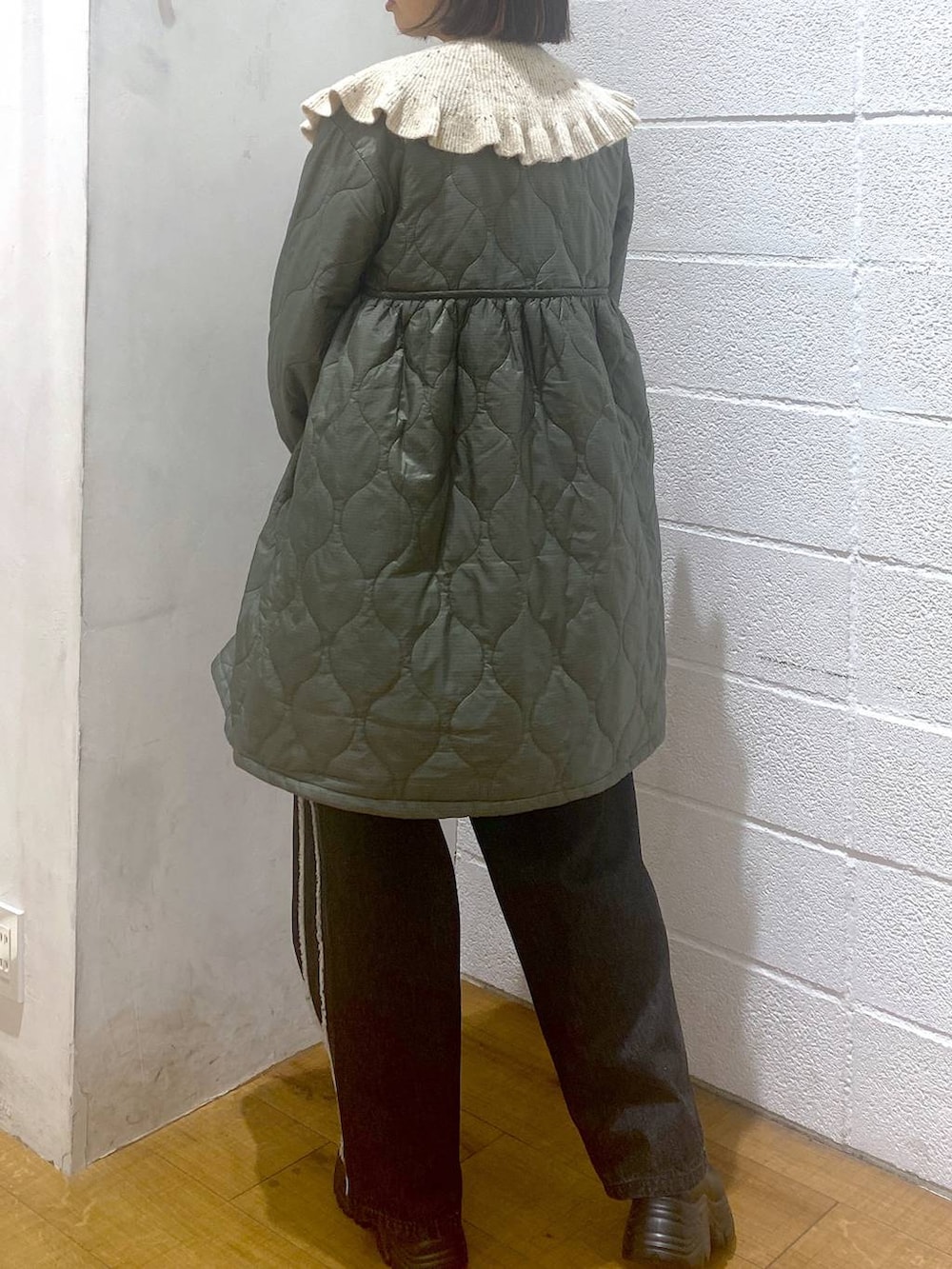 ブラック系のデニムパンツ、グリーン系のミリタリージャケット、ホワイト系のハンドバッグを着用したレディースの秋コーディネートの3枚目の写真
