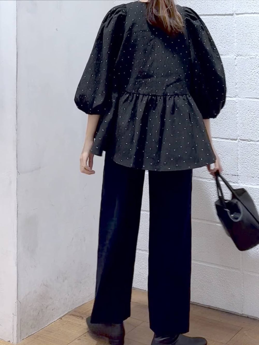 ブラック系のショルダーバッグ、ブラック系のブーツ、ブルー系のスラックスを着用したレディースの冬コーディネートの2枚目の写真