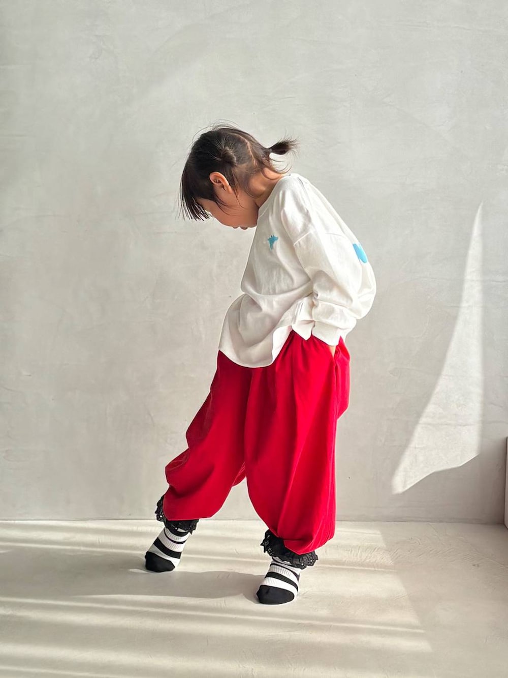 レッド系のスウェットパンツ、ホワイト系のTシャツ/カットソーを着用したキッズの冬コーディネートの2枚目の写真