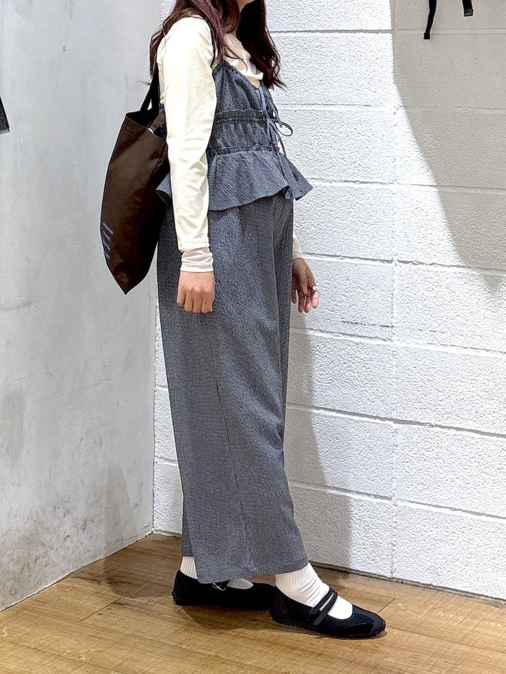 ブラウン系のトートバッグ、ブラック系のスニーカー、ホワイト系のTシャツ/カットソーを着用したレディースの春コーディネートの2枚目の写真