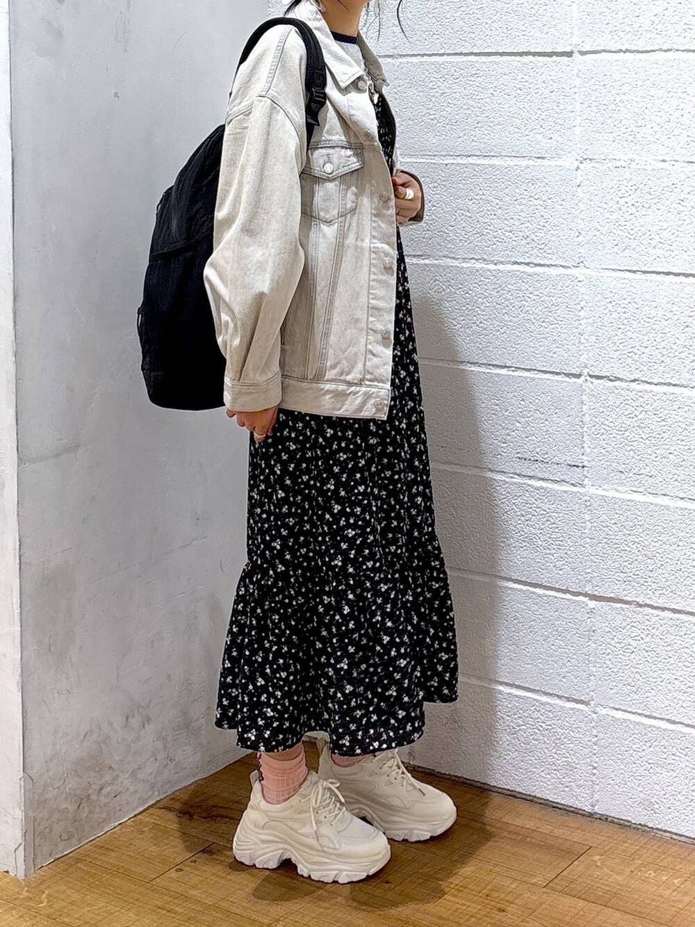 グレー系のデニムジャケット、ホワイト系のスニーカー、グレー系のバックパック/リュックを着用したレディースの春コーディネートの2枚目の写真