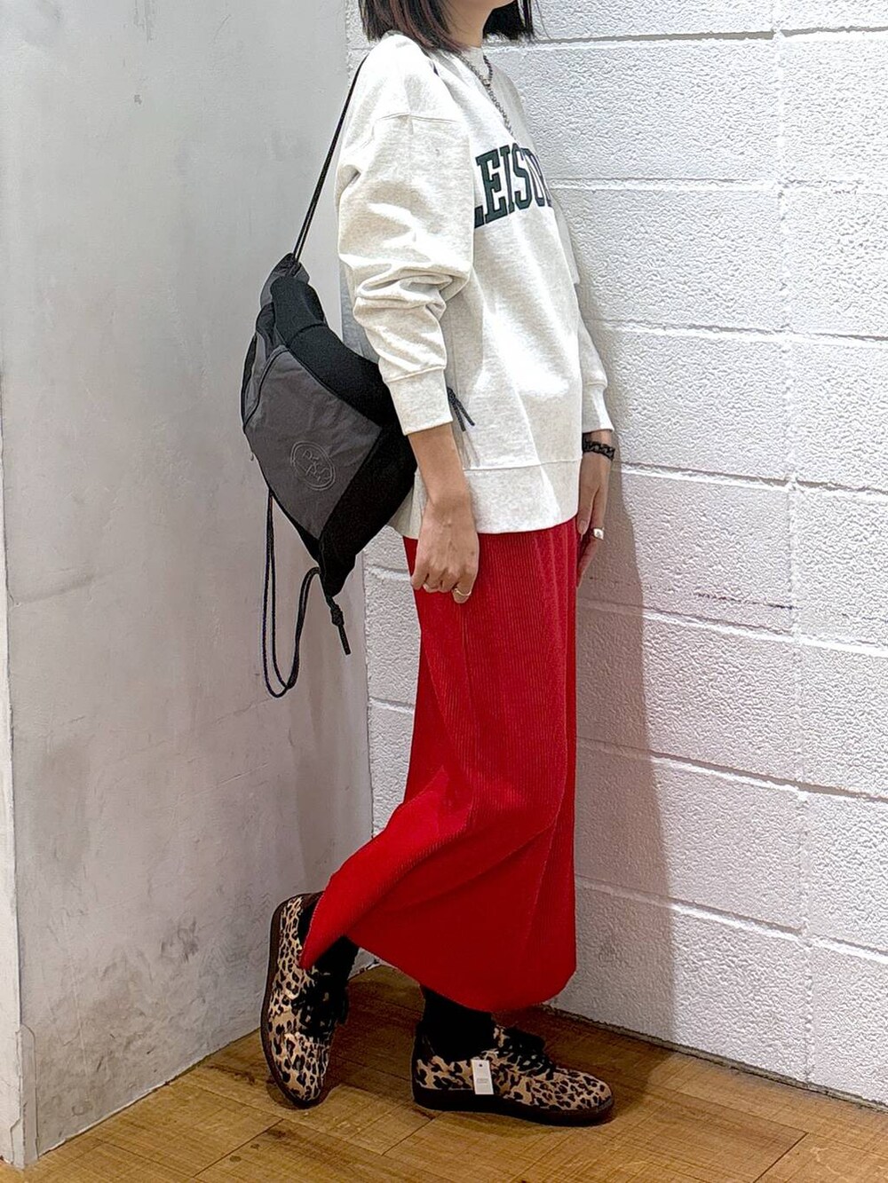 レッド系のスカート、グレー系のスウェット、ブラック系のバックパック/リュックを着用したレディースの冬コーディネートの2枚目の写真