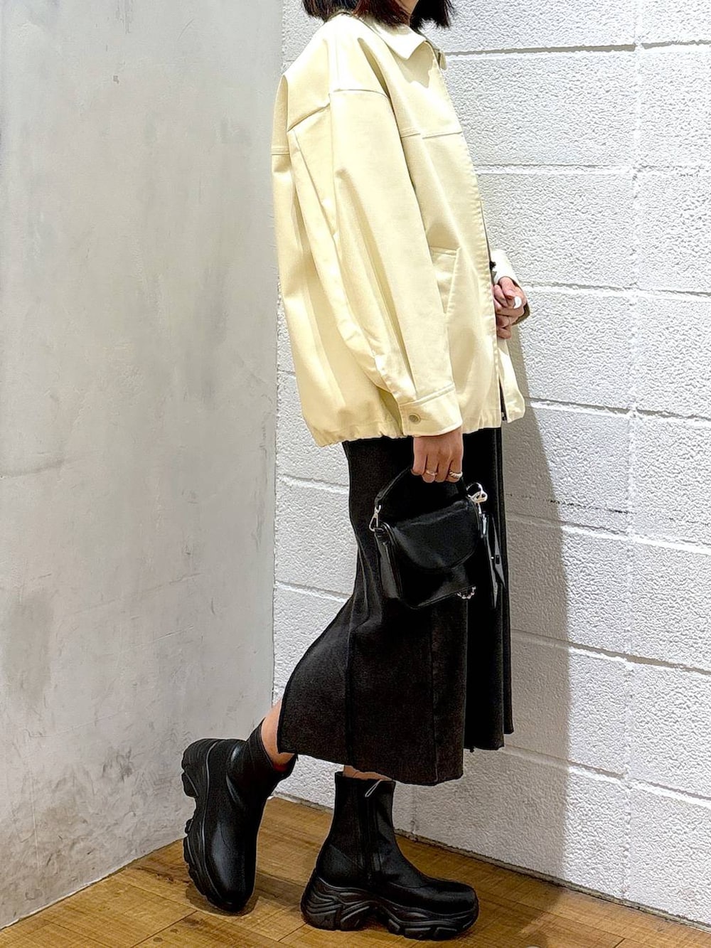 ブラック系のブーツ、ブラック系のショルダーバッグ、ホワイト系のブルゾンを着用したレディースの冬コーディネートの2枚目の写真