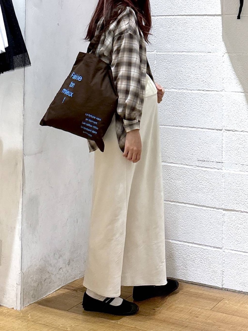 ホワイト系のスカート、ブラウン系のトートバッグ、ブラック系のスニーカーを着用したレディースの春コーディネートの2枚目の写真