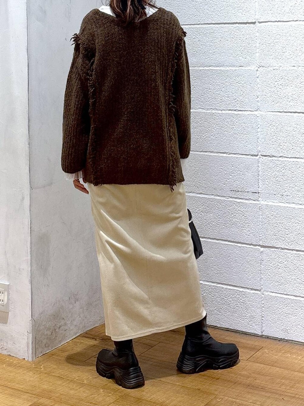 ブラウン系のニット/セーター、ホワイト系のスカート、ホワイト系のTシャツ/カットソーを着用したレディースの冬コーディネートの2枚目の写真