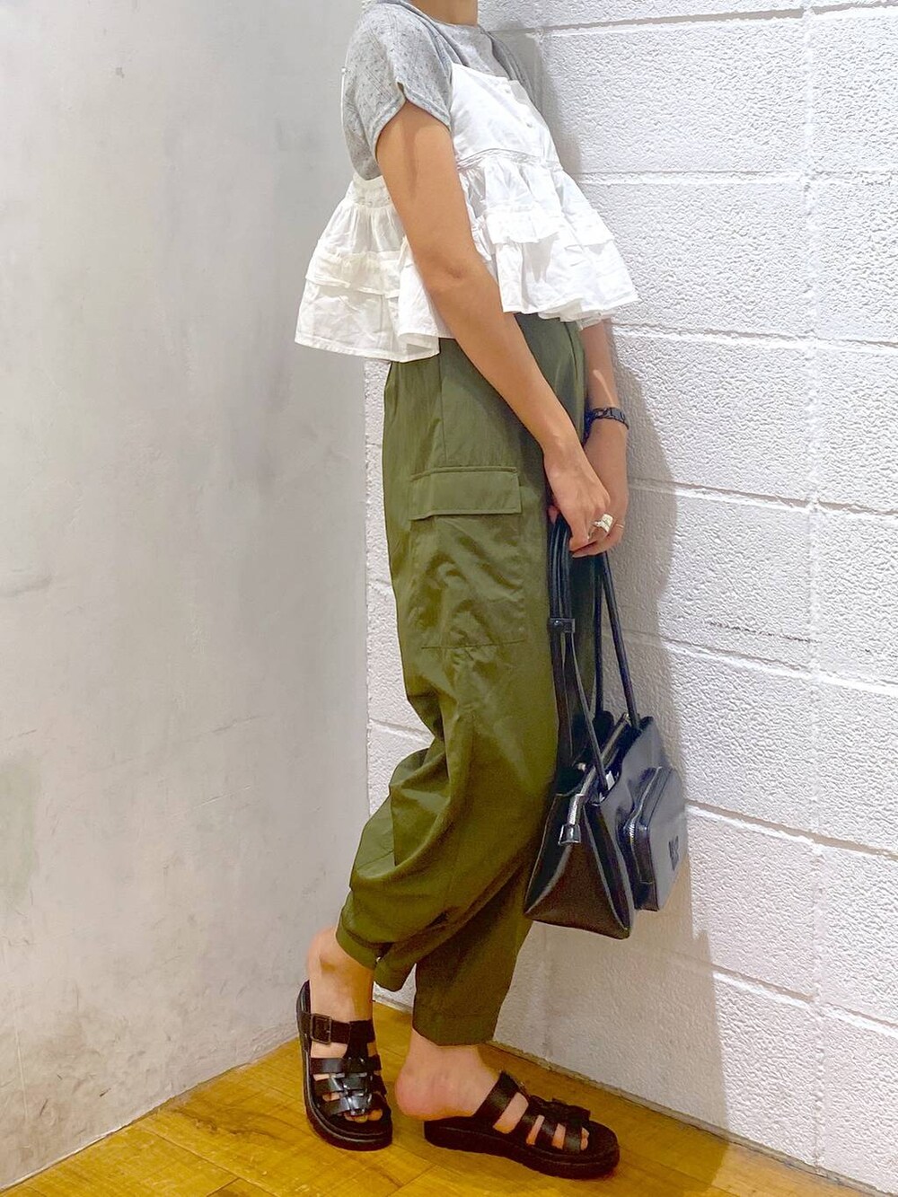 グリーン系のカーゴパンツ、ブラック系のスニーカー、ホワイト系のキャミソールを着用したレディースの夏コーディネートの2枚目の写真