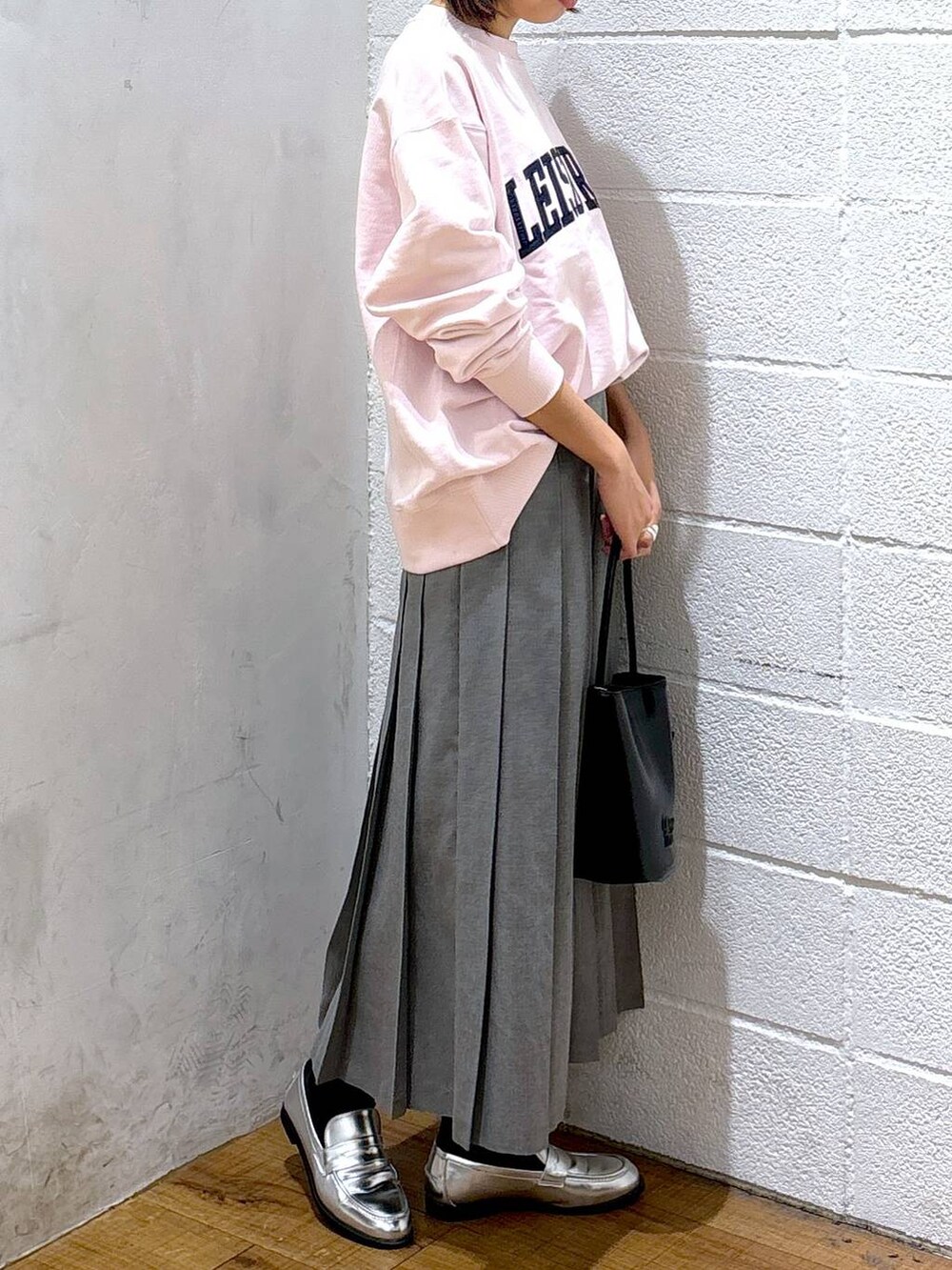 シルバー系のローファー、グレー系のスカート、ピンク系のスウェットを着用したレディースの冬コーディネートの2枚目の写真