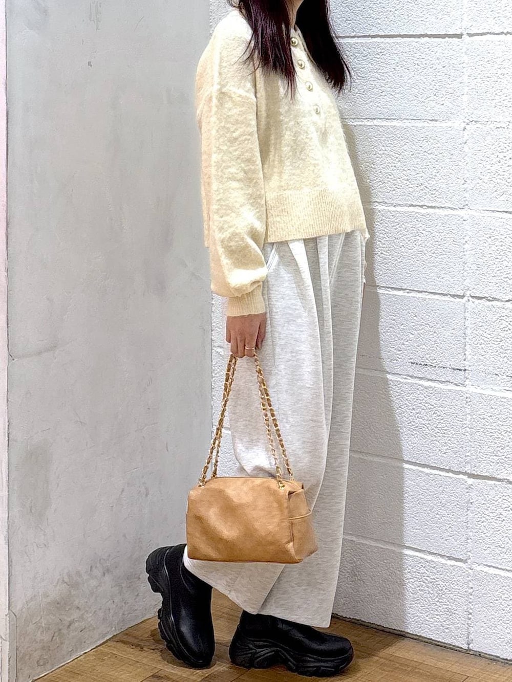 ブラック系のブーツ、グレー系のスウェットパンツ、ホワイト系のニット/セーターを着用したレディースの冬コーディネートの2枚目の写真