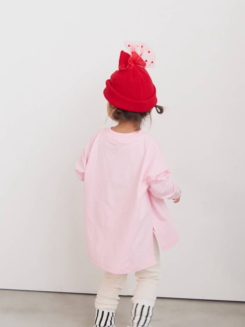 ベージュ系のその他パンツ、ピンク系のTシャツ/カットソー、レッド系のニットキャップ/ビーニーを着用したキッズの秋コーディネートの2枚目の写真
