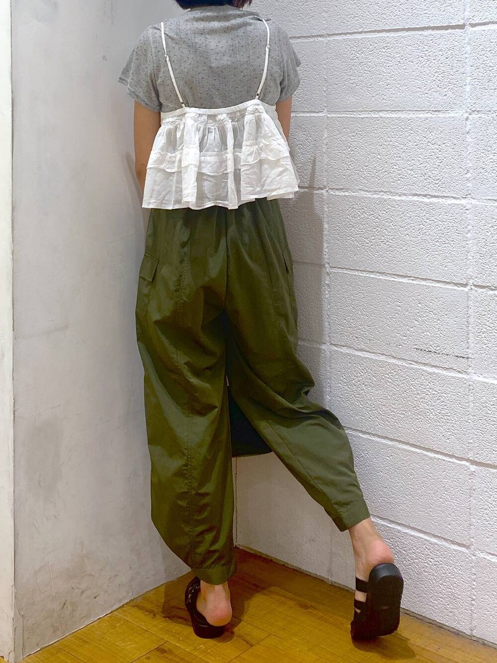 グリーン系のカーゴパンツ、ブラック系のスニーカー、ホワイト系のキャミソールを着用したレディースの夏コーディネートの3枚目の写真