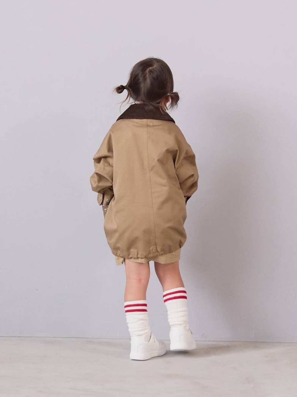 ベージュ系のミリタリージャケット、ベージュ系のスカート、ベージュ系のバンダナ/スカーフを着用したキッズの秋コーディネートの2枚目の写真