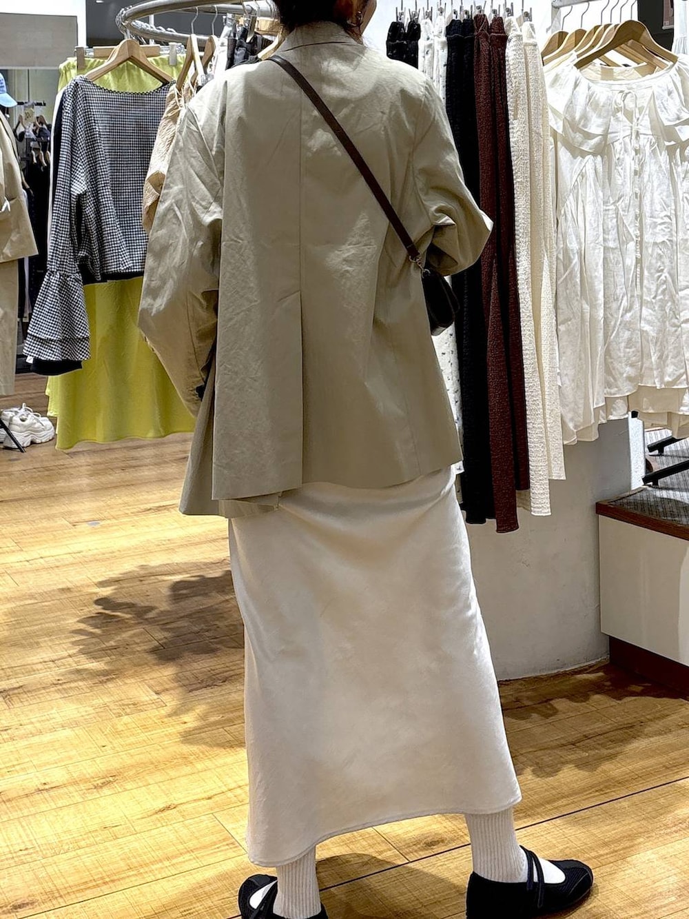 ホワイト系のスカート、ブラック系のスニーカー、ブラウン系のタンクトップを着用したレディースの春コーディネートの3枚目の写真