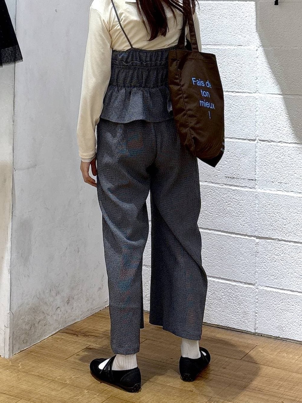 ブラウン系のトートバッグ、ブラック系のスニーカー、ホワイト系のTシャツ/カットソーを着用したレディースの春コーディネートの3枚目の写真