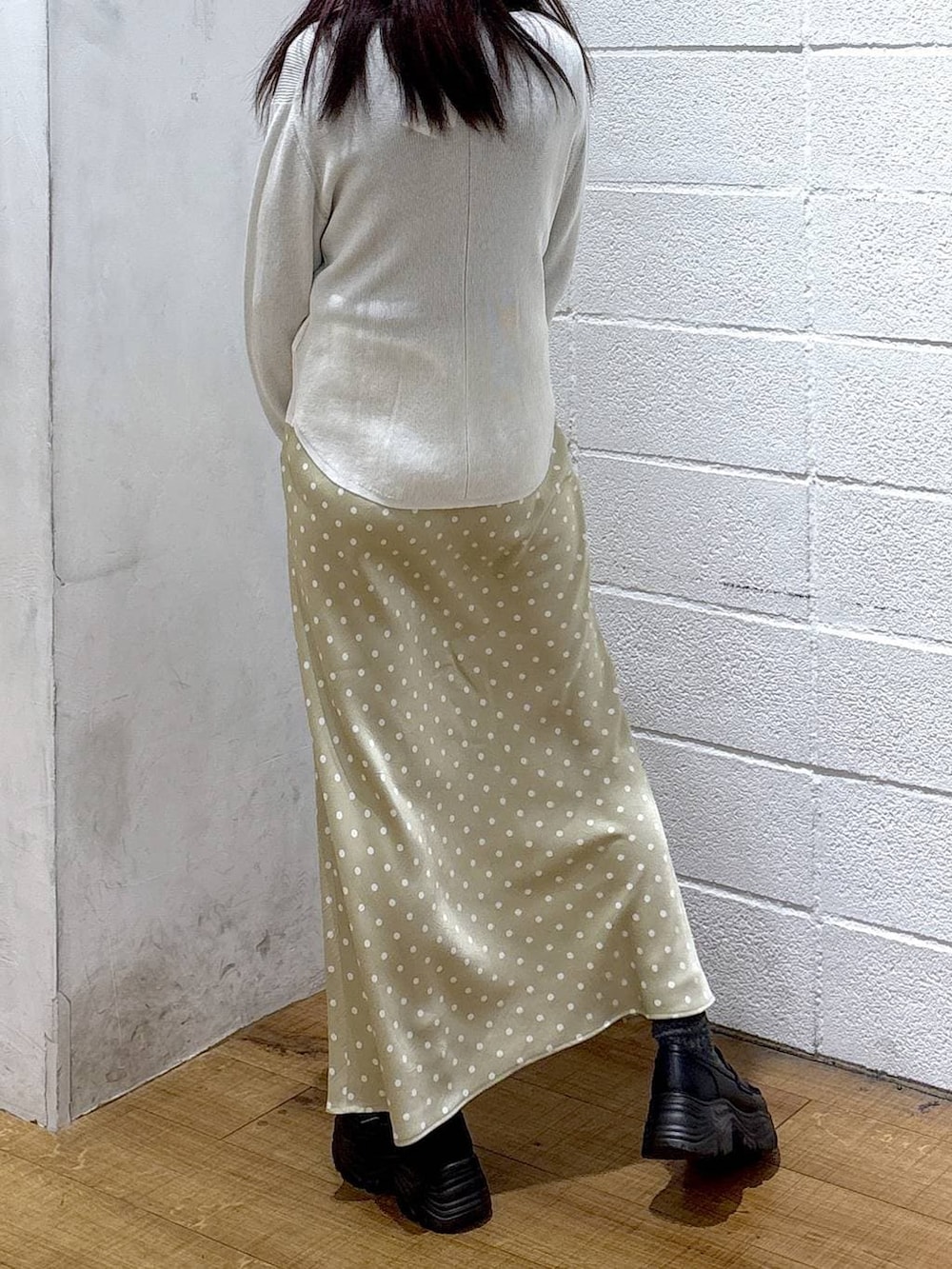 ベージュ系のスカート、ブラック系のニット/セーター、ホワイト系のニット/セーターを着用したレディースの冬コーディネートの2枚目の写真