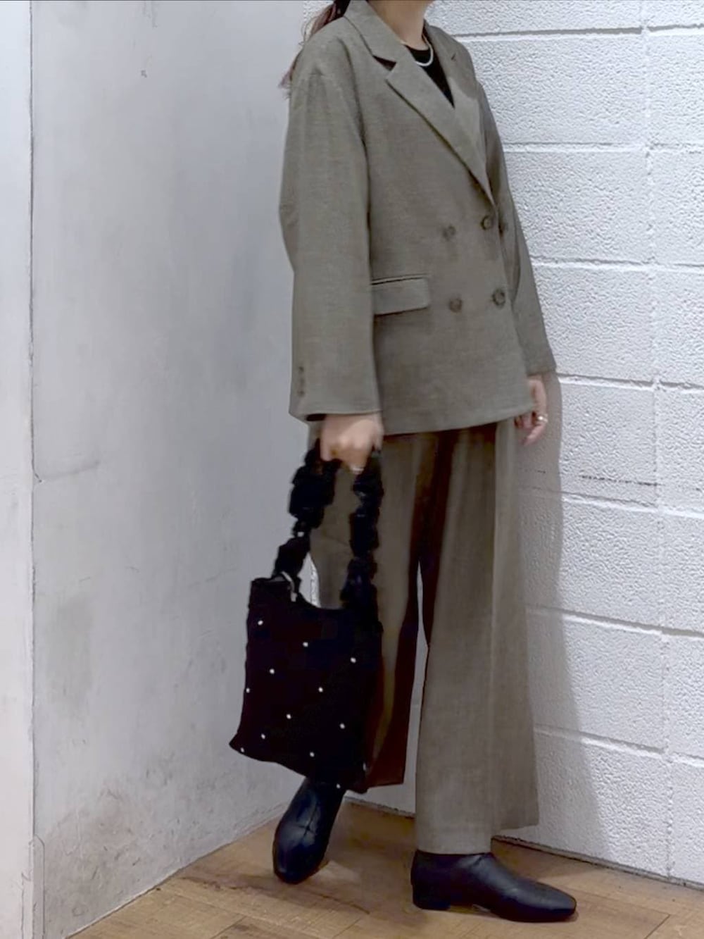 ブラック系のニット/セーター、ブラウン系のテーラードジャケット、ブラウン系のデニムパンツを着用したレディースの冬コーディネートの2枚目の写真