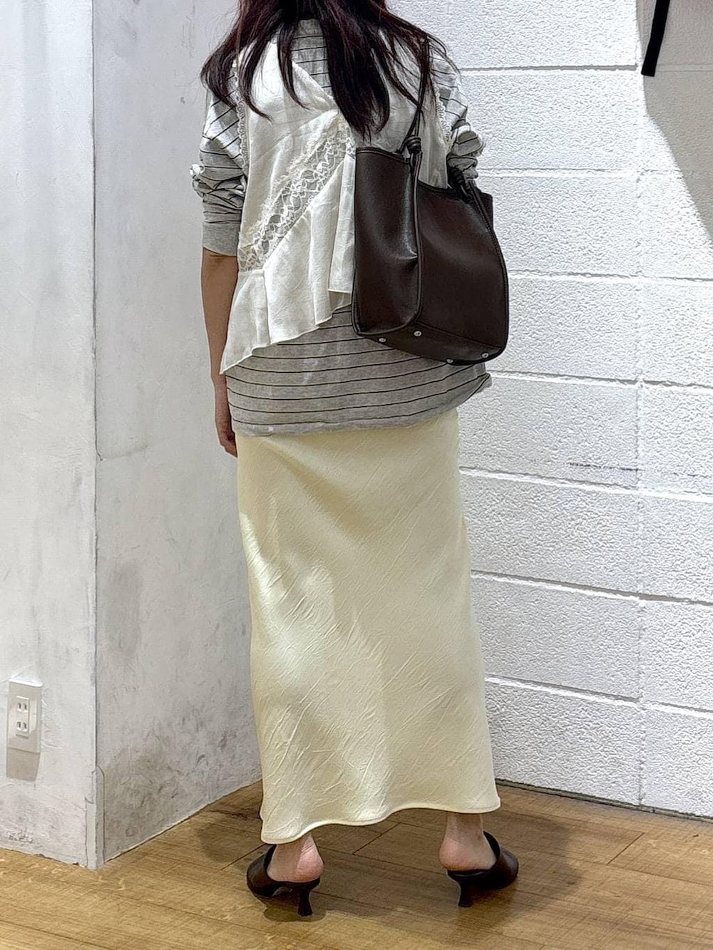 イエロー系のスカート、ブラウン系のサンダル、グレー系のTシャツ/カットソーを着用したレディースの春コーディネートの3枚目の写真