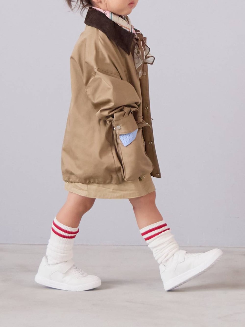 ベージュ系のミリタリージャケット、ベージュ系のスカート、ベージュ系のバンダナ/スカーフを着用したキッズの秋コーディネートの3枚目の写真