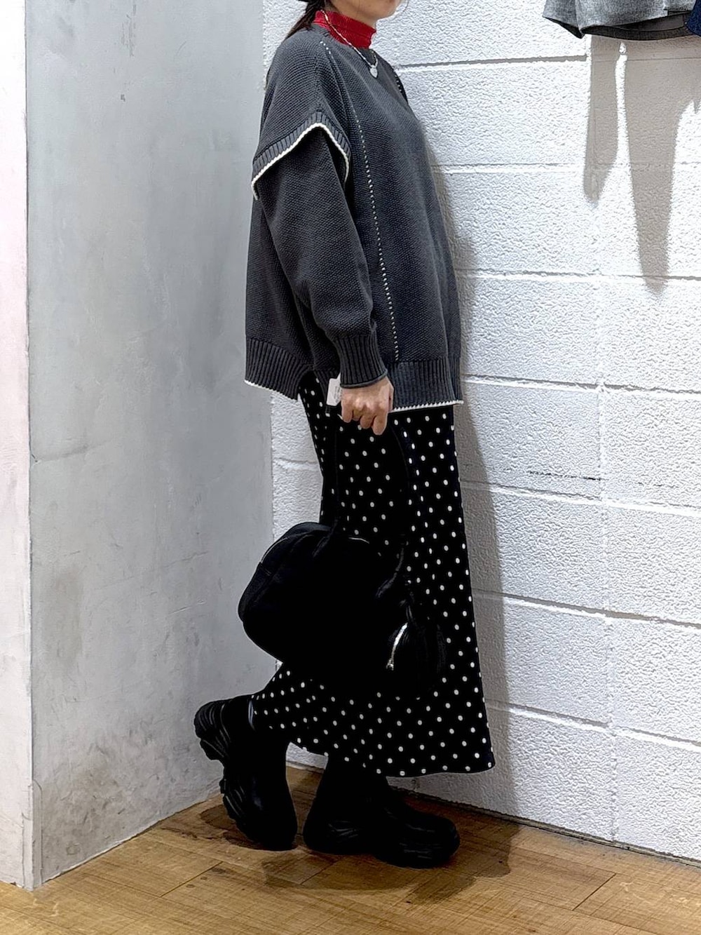 ブラック系のブーツ、ブラック系のスカート、グレー系のニット/セーターを着用したレディースの冬コーディネートの2枚目の写真