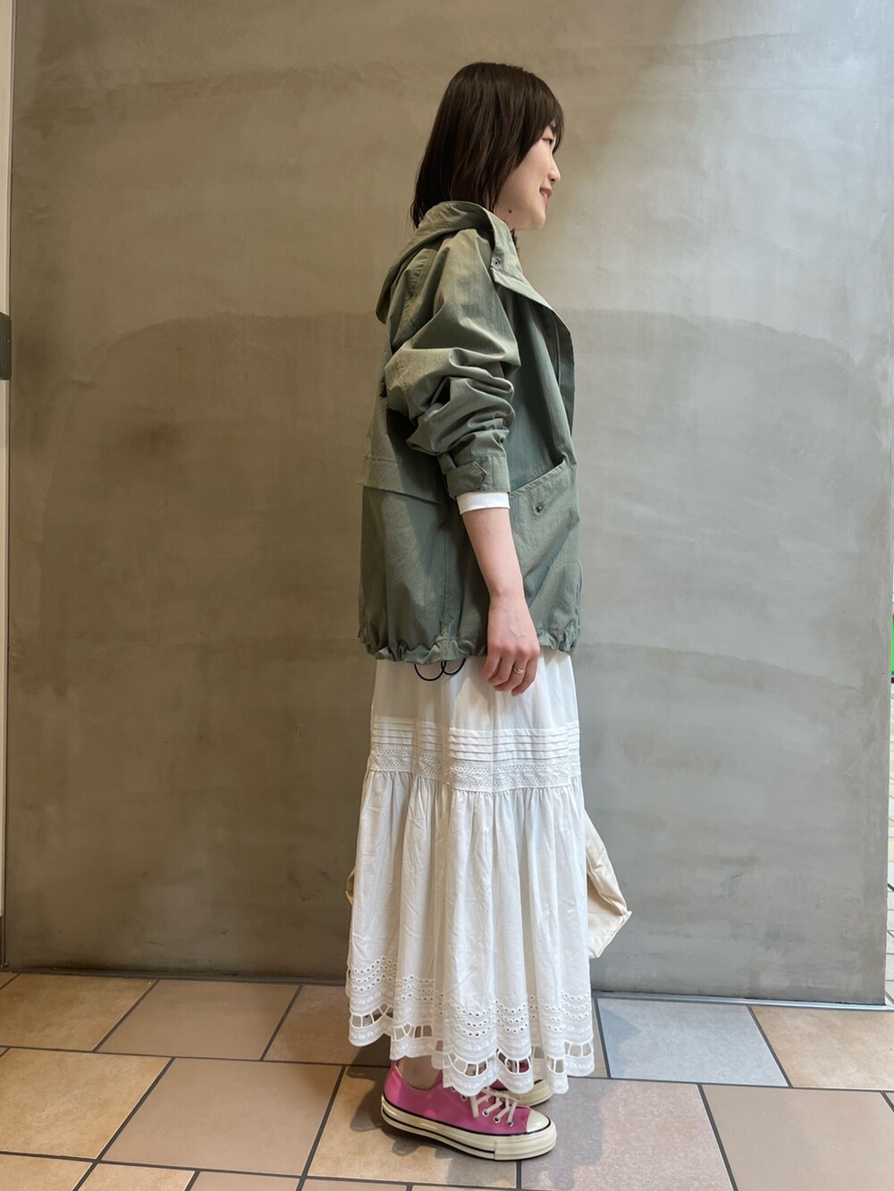 グリーン系のマウンテンパーカー、ホワイト系のTシャツ/カットソー、ホワイト系のトートバッグを着用したレディースの春コーディネートの2枚目の写真