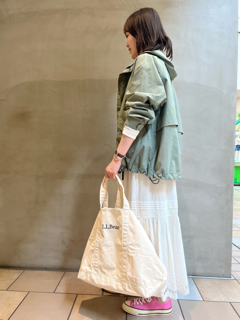 グリーン系のマウンテンパーカー、ホワイト系のTシャツ/カットソー、ホワイト系のトートバッグを着用したレディースの春コーディネートの4枚目の写真