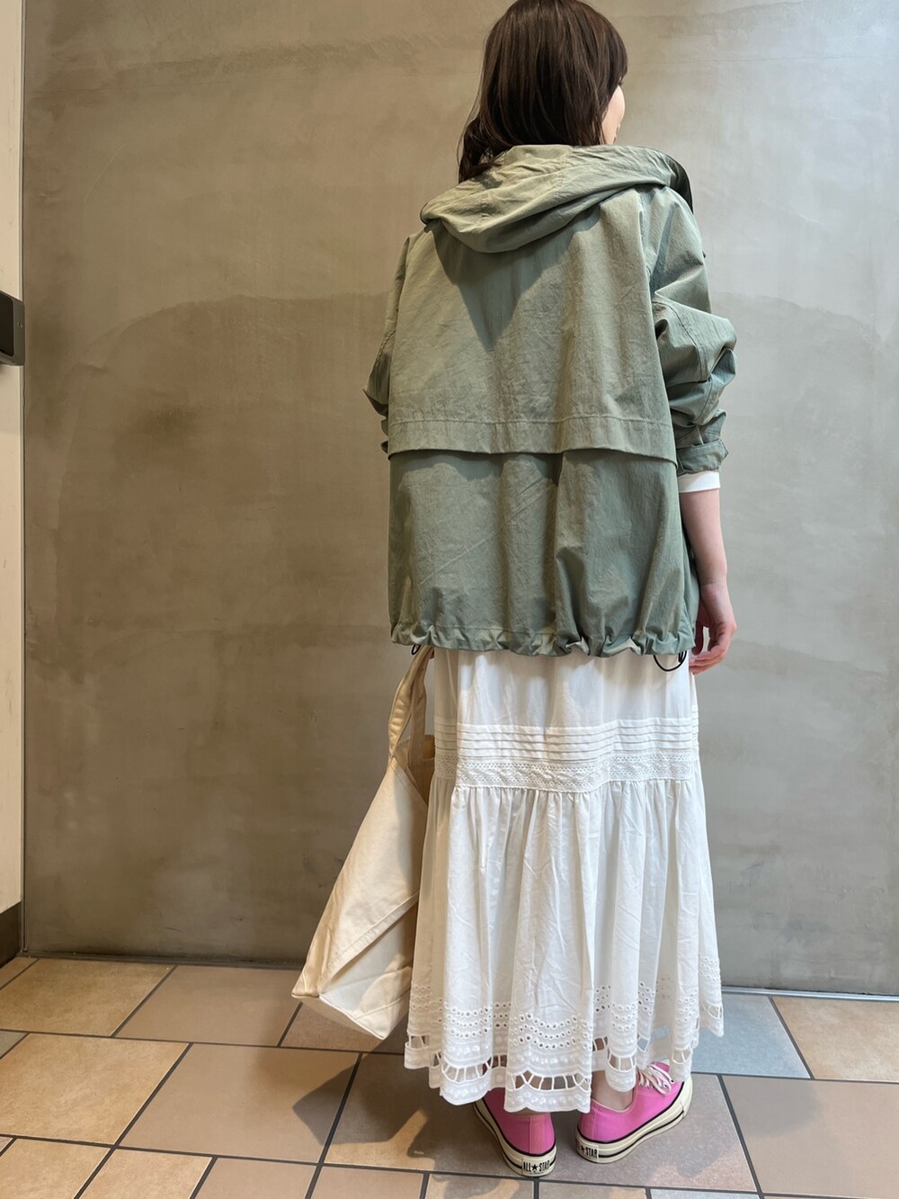 グリーン系のマウンテンパーカー、ホワイト系のTシャツ/カットソー、ホワイト系のトートバッグを着用したレディースの春コーディネートの3枚目の写真